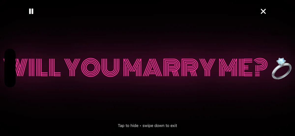 Landscape GlowText player showing “WILL YOU MARRY ME?” in pink neon with the pause and exit controls visible.